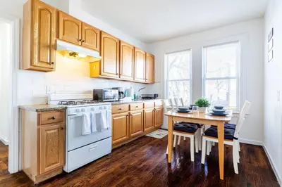 a kitchen with wooden cabinets and a table and a stove at Family Urban: 2BR FREE Pkng Airport NYC Ease in Newark