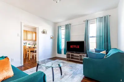 a living room with two blue chairs and a tv at Family Urban: 2BR FREE Pkng Airport NYC Ease in Newark