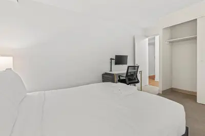 a white bedroom with a bed and a desk at Apartmint at The Metropolitan - Philadelphia in Philadelphia