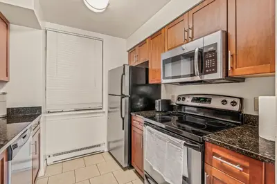 a kitchen with stainless steel appliances and wooden cabinets at Apartmint at The Metropolitan - Philadelphia in Philadelphia