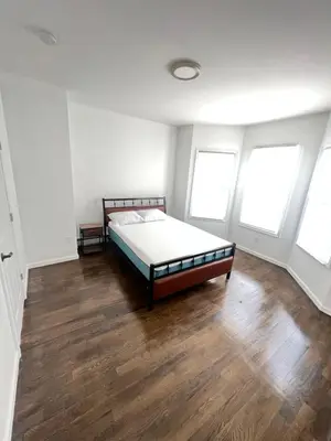 a bedroom with a bed and three windows at Newly renovated furnished home in Newark