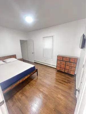 an empty bedroom with a bed and a wooden floor at Newly renovated furnished home in Newark