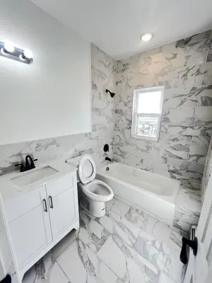 a white bathroom with a toilet and a sink at Newly renovated furnished home in Newark