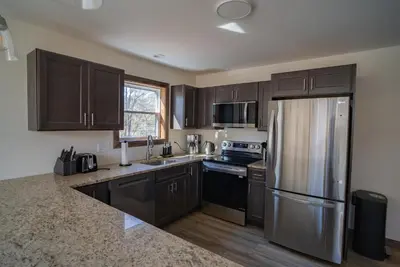 a kitchen with wooden cabinets and a stainless steel refrigerator at Luxury Chalet with hot tub in scenic Poconos in Albrightsville