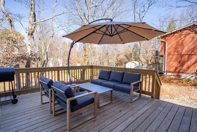 a patio with a table and chairs and an umbrella at Luxury Chalet with hot tub in scenic Poconos in Albrightsville