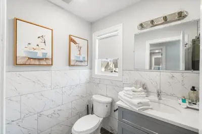 a white bathroom with a toilet and a sink at Orange's Oasis in East Orange