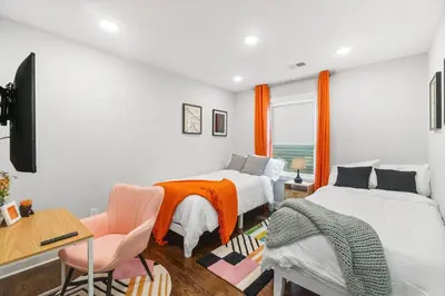 a bedroom with two beds and a desk and a window at Orange's Oasis in East Orange