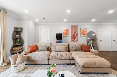 a living room with a tan couch and orange pillows at Orange's Oasis in East Orange