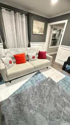 a living room with a white couch with red pillows at Rooms available in a single Family home shared with Host in Willingboro