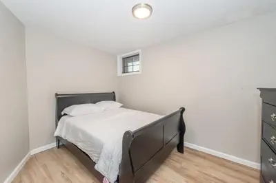 a bedroom with a bed with white sheets and a window at Cozy Basement 2 Bed in Passaic in Passaic