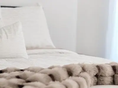 a white bed with a furry blanket on it at Cozy Pocono Escape in Tobyhanna