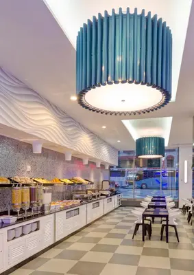 a restaurant with tables and chairs and a large chandelier at Riu Plaza New York Times Square in New York