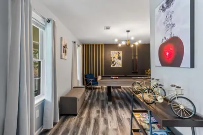 a living room with a table and a bike on the wall at Emerald Lakes Poconos Retreat Game Room, Firepit & Sleeps 10 in Long Pond