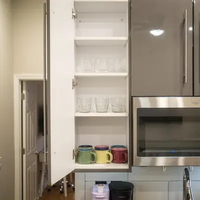 a kitchen with a cupboard with cups and a microwave at Cozy 1BD With Balcony in Philadelphia