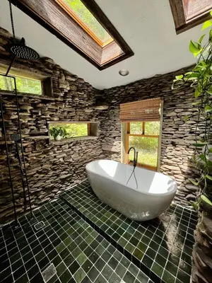 a bath tub in a bathroom with a stone wall at Stunning Catskills Cabin in Margaretville