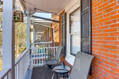 a porch with two chairs and a brick wall at 2 Mi to Dtwn Harrisburg Escape with Furnished Deck! in Harrisburg