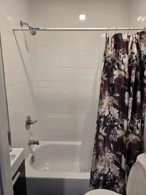 a bathroom with a tub and a toilet and a shower curtain at favour family house in Newark