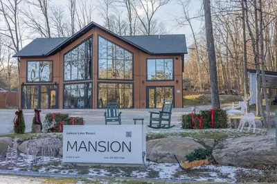 a large house with a sign in front of it at Luxury 6BR Mansion - Lakefront, Sauna, Hot Tub in Scotrun