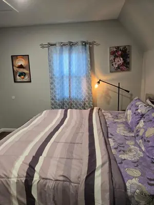 a bedroom with a bed with a striped blanket and a window at Rose room 8 in Newark