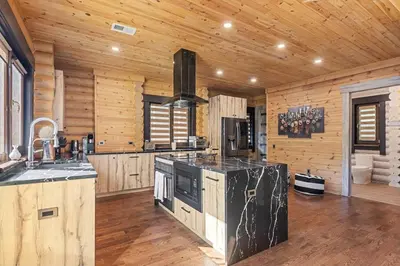 a kitchen with wooden walls and a stove top oven at Log House Chalet, Volleyball field, Sauna, Hot Tub in Henryville