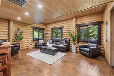 a living room with leather furniture in a log cabin at Log House Chalet, Volleyball field, Sauna, Hot Tub in Henryville