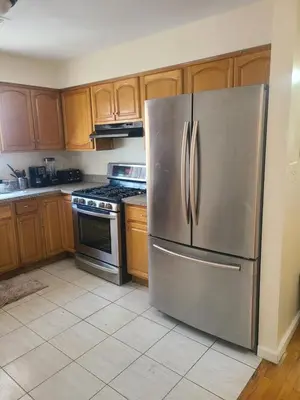a stainless steel refrigerator in a kitchen with wooden cabinets at Grace Room 4 in Newark