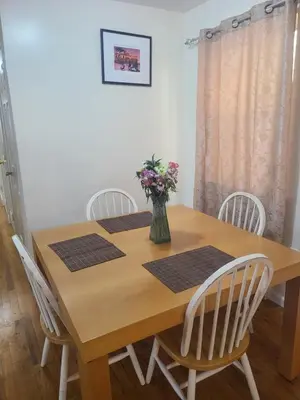 a wooden table with chairs and a vase of flowers on it at Grace Room 4 in Newark