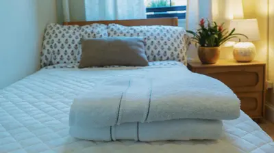 a large white bed with a pillow and a table at Interfaith 21st Street in New York