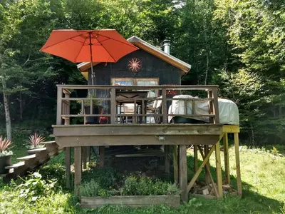 a house with an umbrella on top of a deck at Cozy Unique Tiny Cabin with Beautiful Views in Livingston Manor, New York in Livingston Manor
