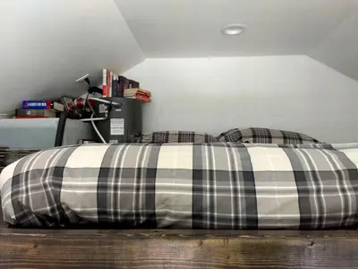 a bed with a black and white plaid blanket at Cozy Unique Tiny Cabin with Beautiful Views in Livingston Manor, New York in Livingston Manor