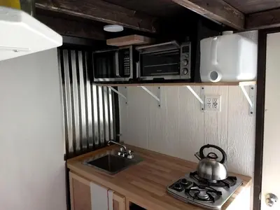 a kitchen with a sink and a stove and microwave at Cozy Unique Tiny Cabin with Beautiful Views in Livingston Manor, New York in Livingston Manor