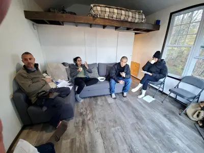 a group of people sitting on a couch in a room at Cozy Unique Tiny Cabin with Beautiful Views in Livingston Manor, New York in Livingston Manor