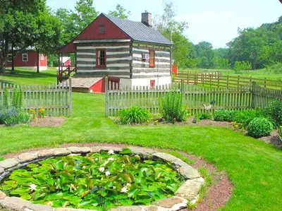 a garden with a house and a pond in the yard at Secluded and Rustic Cabin with a Private Deck near Reading, Pennsylvania in Robesonia