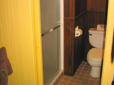 a bathroom with a toilet and a glass shower door at Secluded and Rustic Cabin with a Private Deck near Reading, Pennsylvania in Robesonia