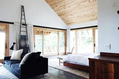 a bedroom with a bed and a couch and windows at Luxurious Modern Chalet Rental on Top of the Shawangunk Mountains in New York in Cragsmoor