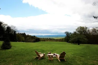 a picnic table and two chairs in a field at Luxurious Modern Chalet Rental on Top of the Shawangunk Mountains in New York in Cragsmoor
