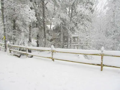 a fence covered in snow with trees in the background at Stunning Weekend Getaway near Hickory Run State Park in Pennsylvania in Jim Thorpe