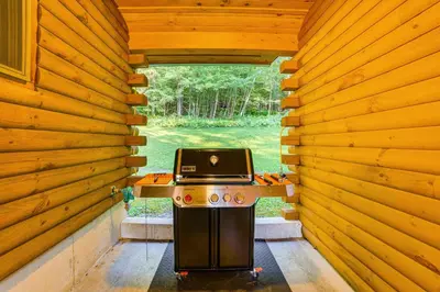 a stove in a log cabin with a laptop on it at West Branch Delaware River Cozy Cabin Retreat! in Deposit