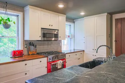 a kitchen with white cabinets and a red stove top oven at John Quigley House - Downtown New Hope in New Hope