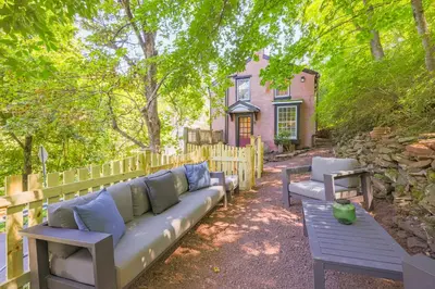 a bench with blue pillows sitting in front of a house at John Quigley House - Downtown New Hope in New Hope