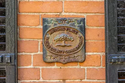 a sign on the side of a brick wall at John Quigley House - Downtown New Hope in New Hope