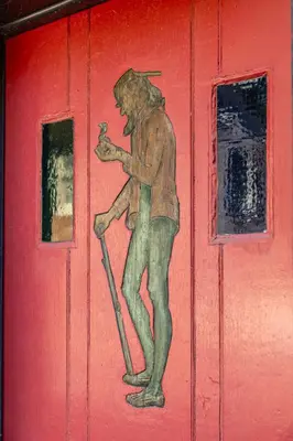 a painting of a man holding a cane on a red door at John Quigley House - Downtown New Hope in New Hope