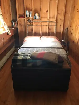 a bed in a room with a wooden wall at Rustic Cabin Retreat on the Ten Mile River in Narrowsburg, New York in Narrowsburg