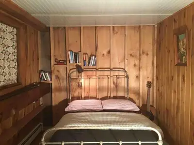 a bed in a room with a wooden wall at Rustic Cabin Retreat on the Ten Mile River in Narrowsburg, New York in Narrowsburg