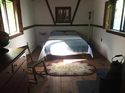 a bedroom with a bed and a rug on the floor at Rustic Cabin Retreat on the Ten Mile River in Narrowsburg, New York in Narrowsburg
