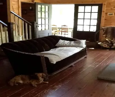 a dog laying on the floor next to a couch at Charming Cottage Rental with Antique Decor in Narrowsburg, New York in Narrowsburg
