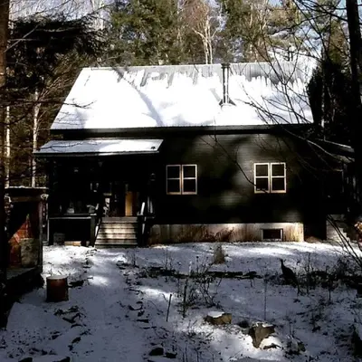 a black house with snow on the roof at Charming Cottage Rental with Antique Decor in Narrowsburg, New York in Narrowsburg