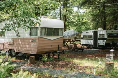 two rvs parked next to each other in a forest at Vintage Shasta Camper for the best of NYC Glamping in Livingston Manor