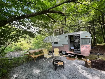 a trailer with a picnic table and an umbrella at Vintage Shasta Camper for the best of NYC Glamping in Livingston Manor