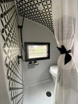 a bathroom with a shower curtain and a toilet at Vintage Shasta Camper for the best of NYC Glamping in Livingston Manor